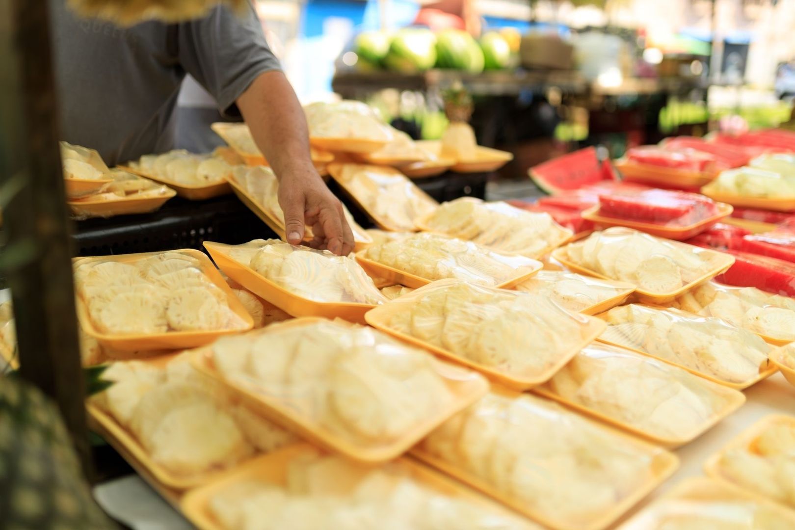 Marktkraam met verpakte voedingsmiddelen en een hand die een schaal aanwijst